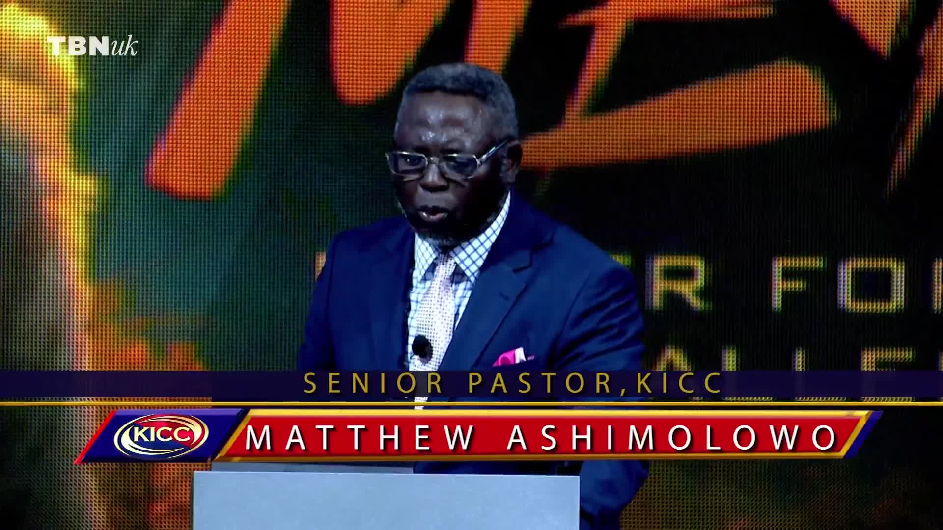 Matthew Ashimolowo, Senior Pastor of KICC, is speaking into a microphone on a stage, his words likely broadcast by TBN UK. He's wearing a blue suit and tie, with a backdrop of warm colors behind him.
Matthew Ashimolowo, Senior Pastor of KICC, is speaking into a microphone on a stage, his words likely broadcast by TBN UK. He's wearing a blue suit and tie, with a backdrop of warm colors behind him.