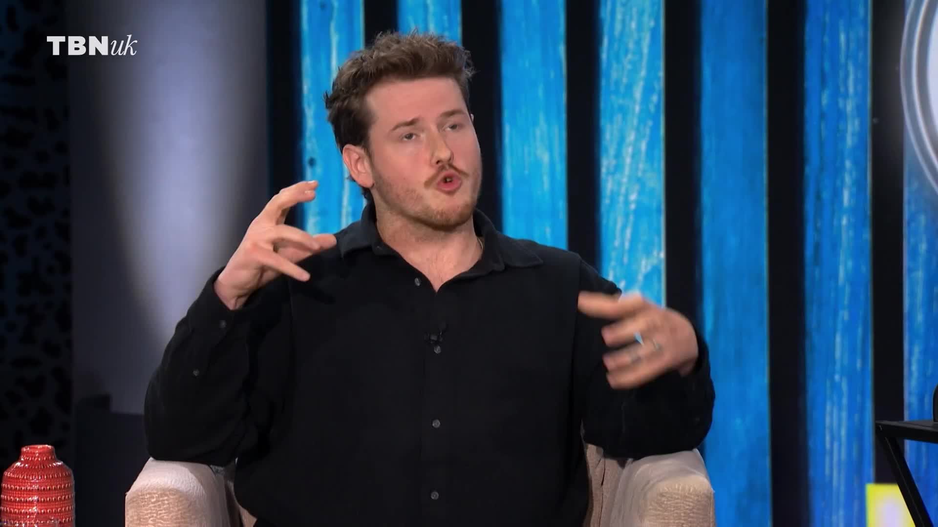 He's gesturing expansively with both hands as he speaks, his expression animated. The TBN UK logo is visible in the corner of the screen.
He's gesturing expansively with both hands as he speaks, his expression animated. The TBN UK logo is visible in the corner of the screen.