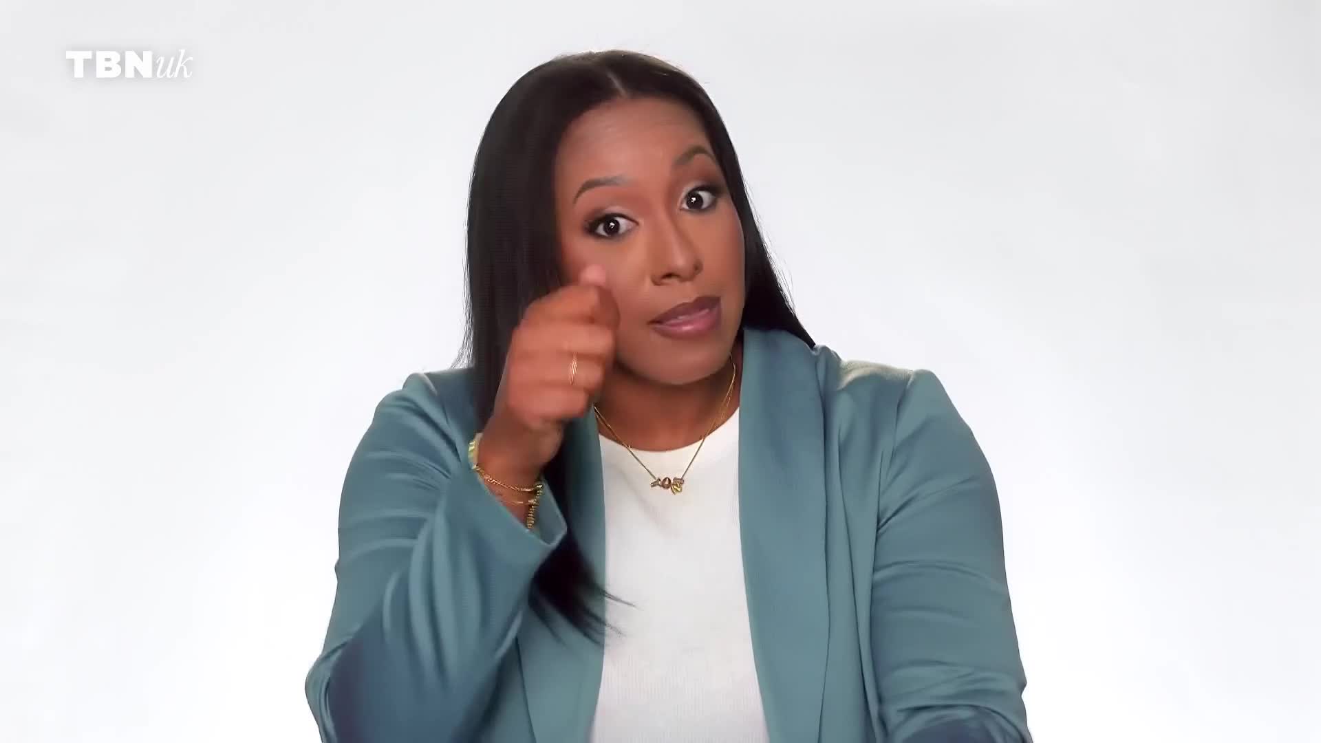 A woman in a teal blazer gestures with her right hand, pointing towards her eye. The TBN UK logo appears in the top left corner. A woman in a teal blazer gestures with her right hand, pointing towards her eye. The TBN UK logo appears in the top left corner.