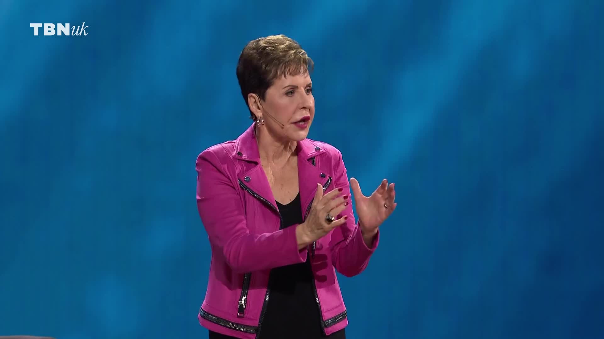 A woman in a bright pink jacket speaks with her hands animated. The TBN UK logo appears in the corner of the screen. A woman in a bright pink jacket speaks with her hands animated. The TBN UK logo appears in the corner of the screen.