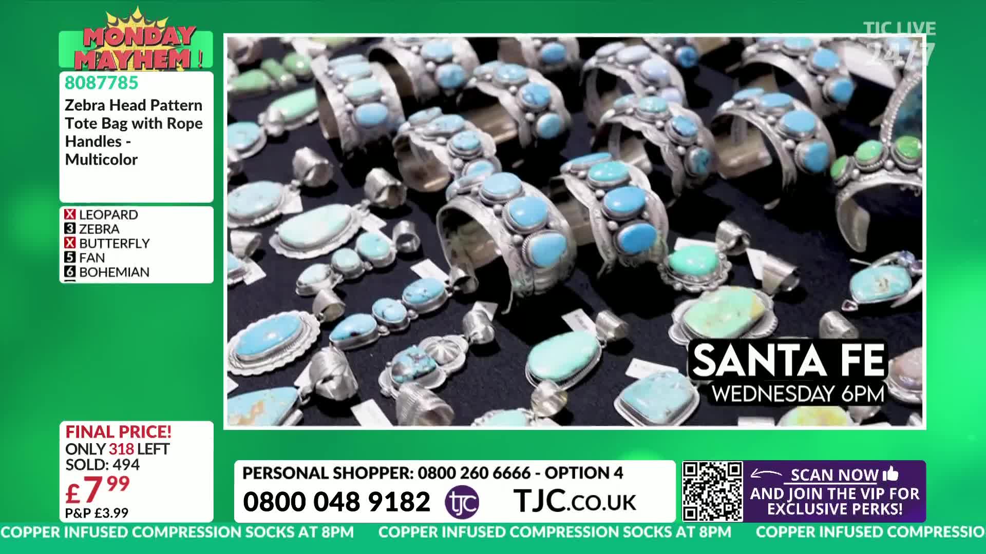 A display of silver jewelry with turquoise stones sits on a dark surface, illuminated by bright studio lights. The TJC logo and a countdown for a Santa Fe sale are visible on the screen.
