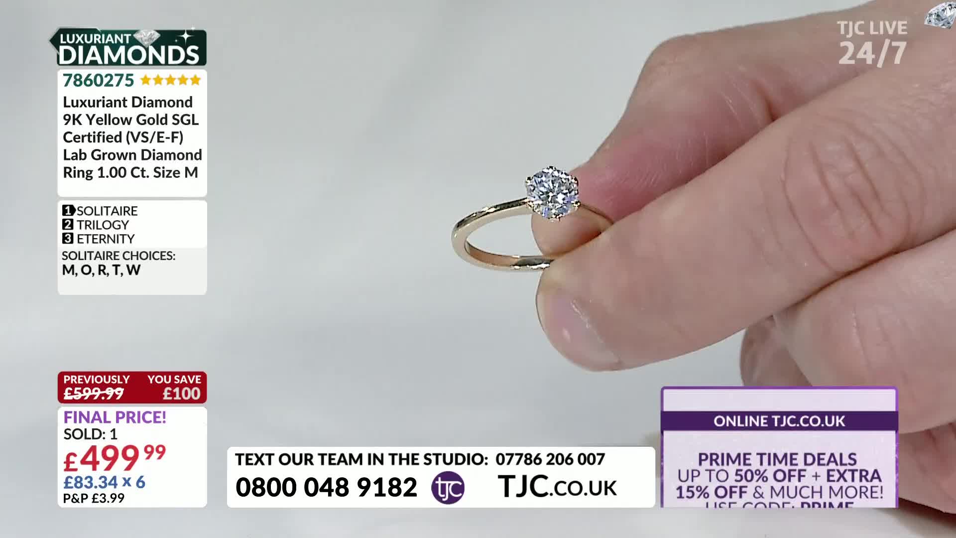 A hand presents a gold ring with a large, sparkling diamond. The ring is held up against a white background, presumably for a jewelry sale on TJC.
