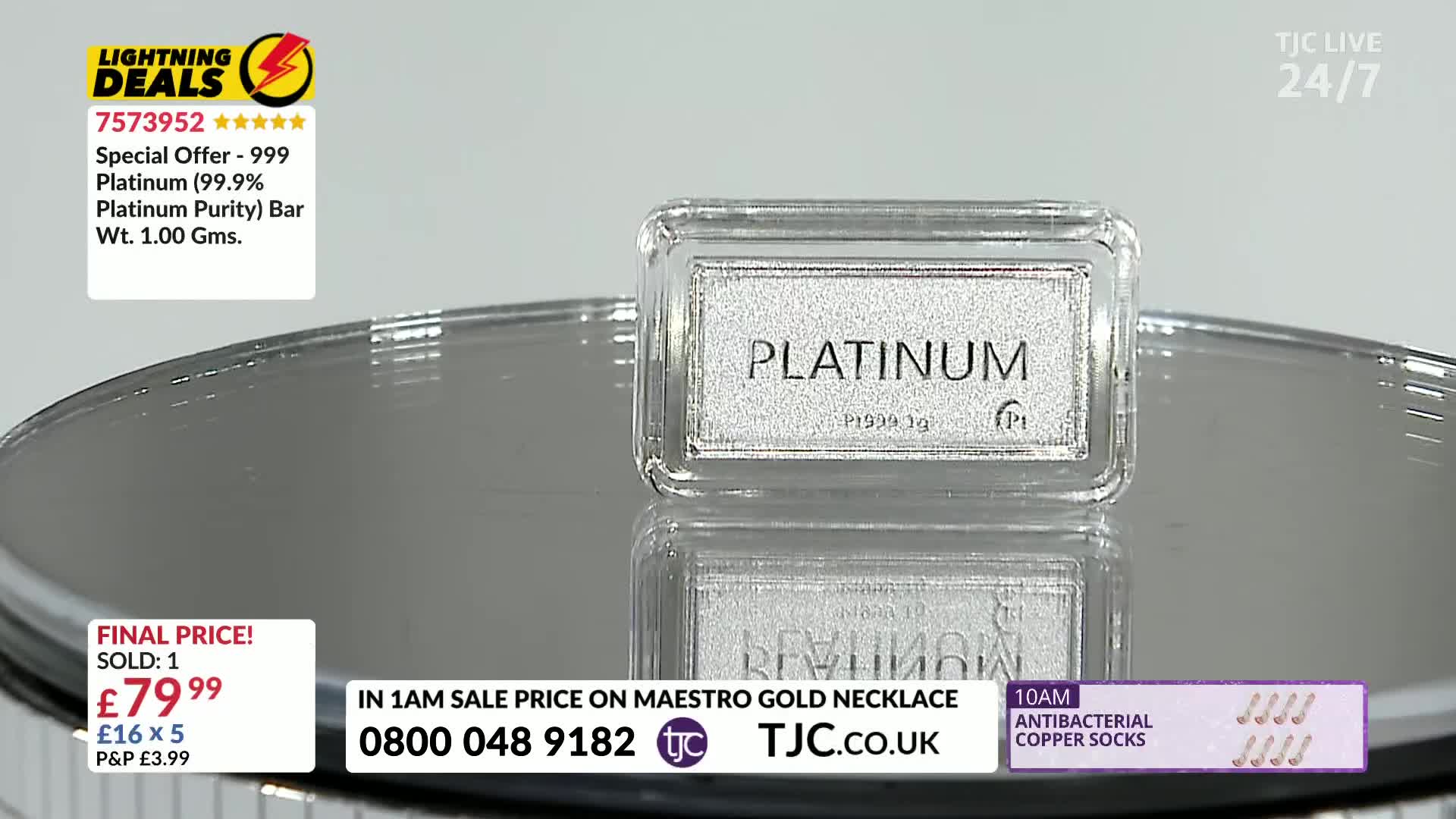 A small platinum bar, encased in a clear plastic box, sits on a reflective surface. The TJC logo is visible, and the final price of the item is displayed.

