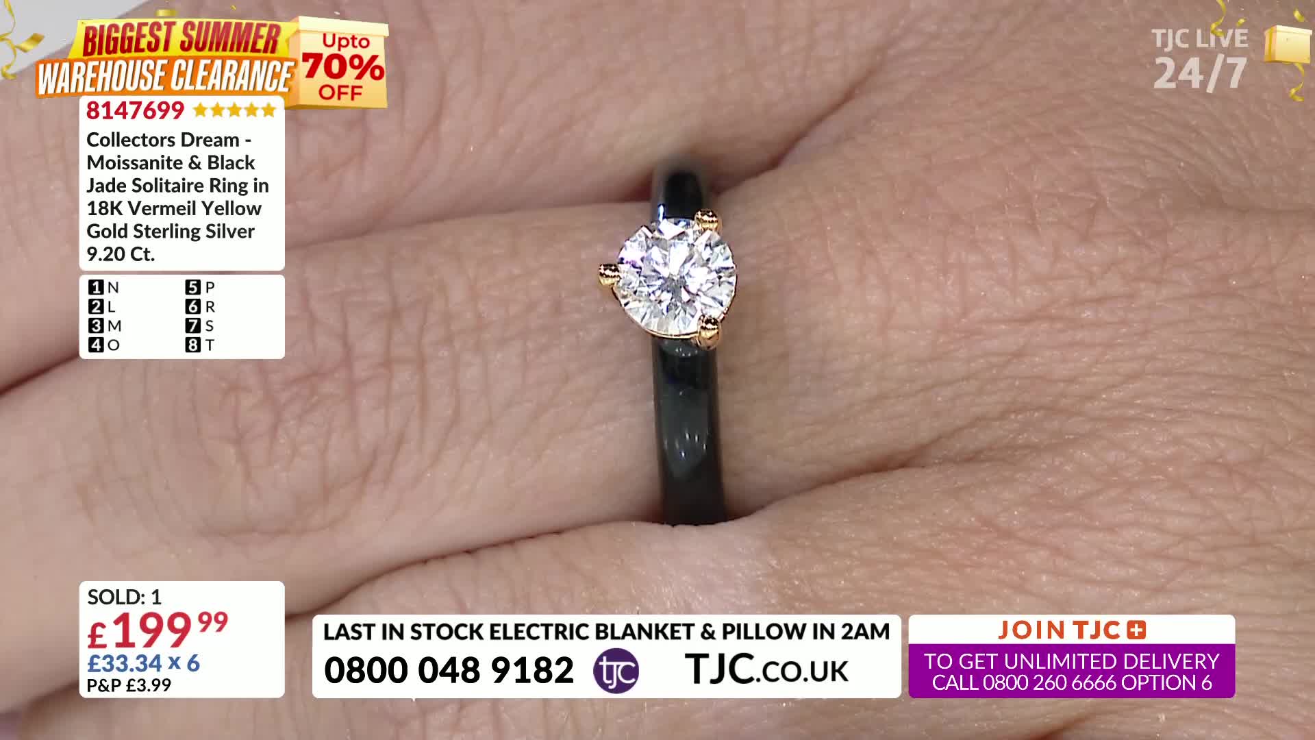 A hand holds a ring, the black band contrasting with the bright, round stone. The TJC logo is visible, and the price is clearly displayed.
