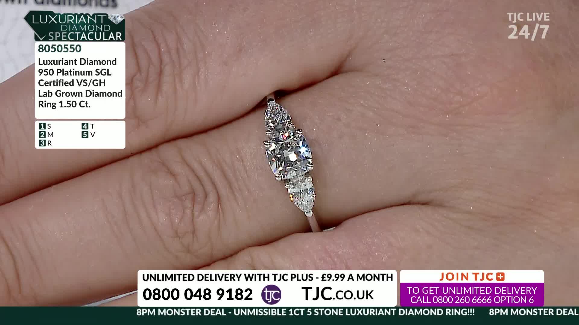 A hand, with a ring featuring a central diamond and smaller side stones, is held up for display. The TJC broadcast is advertising the ring, with details and a phone number visible on the screen.
