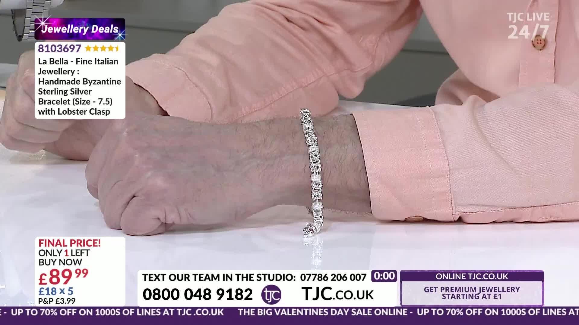 A silver bracelet with many small, clear stones is clasped around a wrist. The delicate chain of the bracelet catches the light as the hand moves slightly.