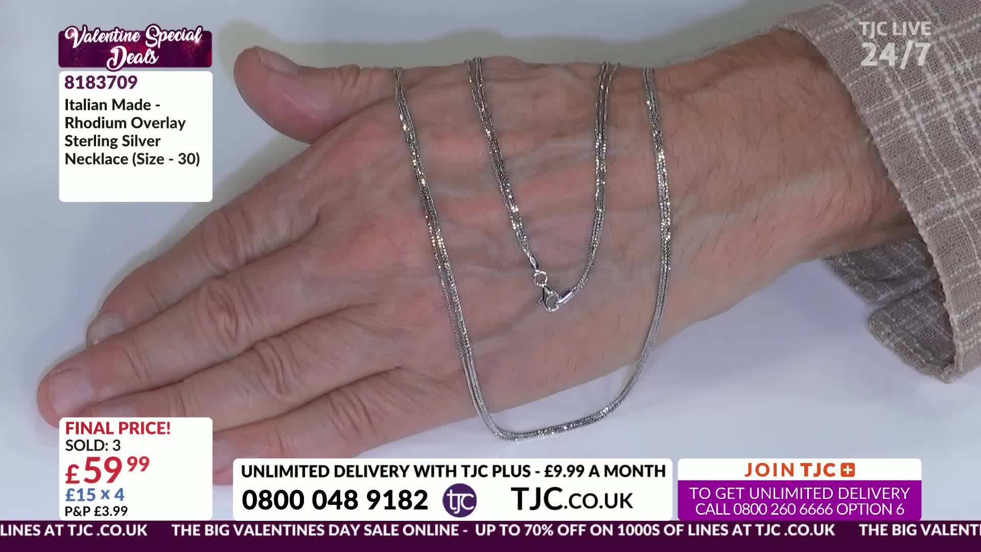 A slender, silver necklace lies draped across an outstretched hand. The delicate links catch the light as the hand shifts slightly.