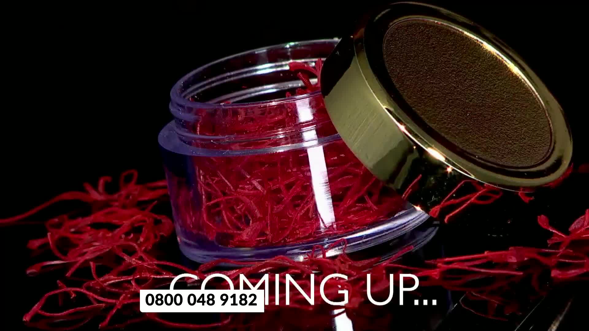 A small glass jar overflows with vibrant red threads, scattered around its base. A golden lid rests askew, hinting at the precious contents within.