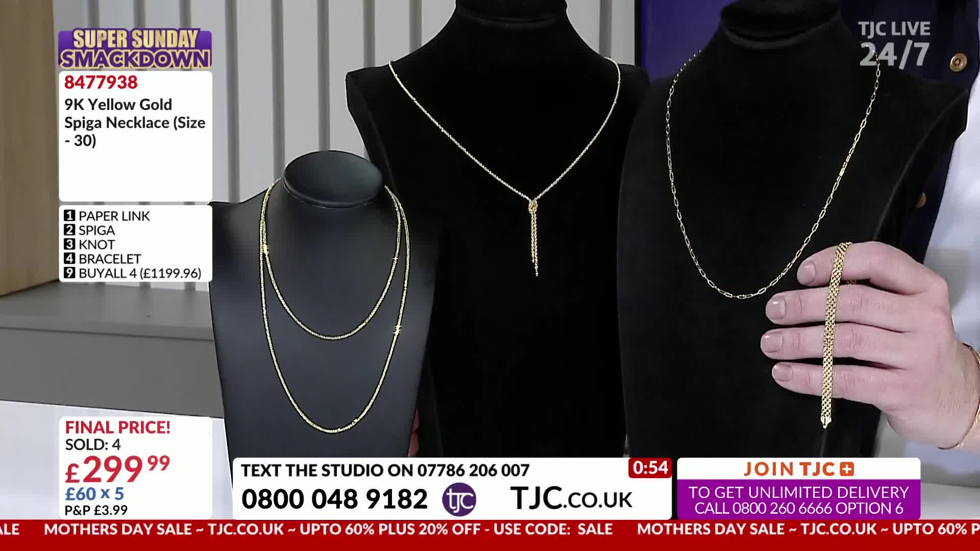 A hand holds up a delicate gold bracelet, its links catching the light. Three gold necklaces, displayed on black busts, shimmer under the studio lights.