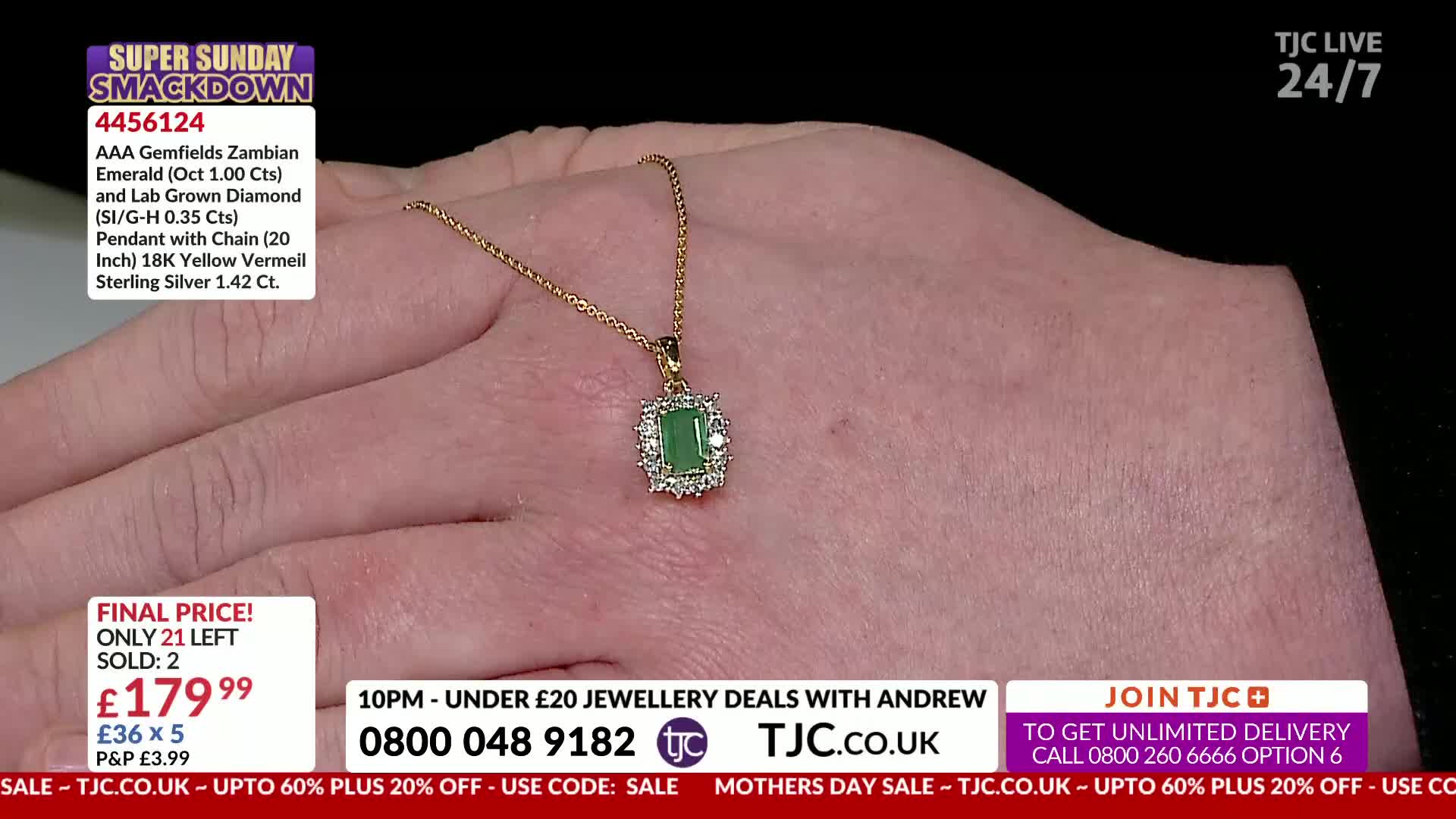 A delicate gold chain holds a rectangular green emerald, surrounded by small diamonds. The pendant rests on a person's hand, displayed against a dark background.