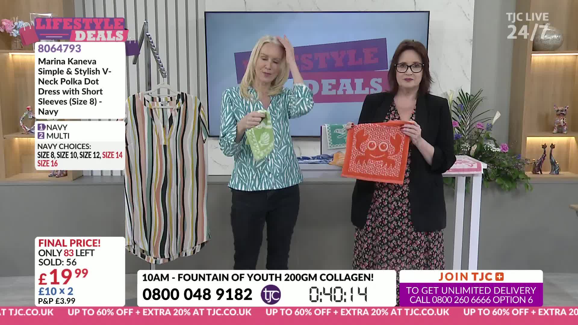 Two women stand on a set, one holding a green bandana and the other an orange one with a crab design. A striped dress hangs on a mannequin to the left of the frame.