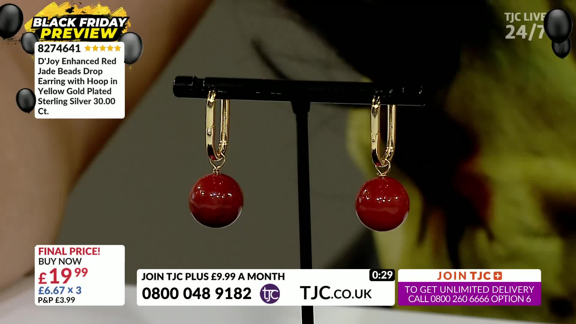 A pair of gold-plated sterling silver earrings, each with a smooth, round red bead, dangle from a black display stand. The TJC logo and pricing information are visible at the bottom of the screen.
