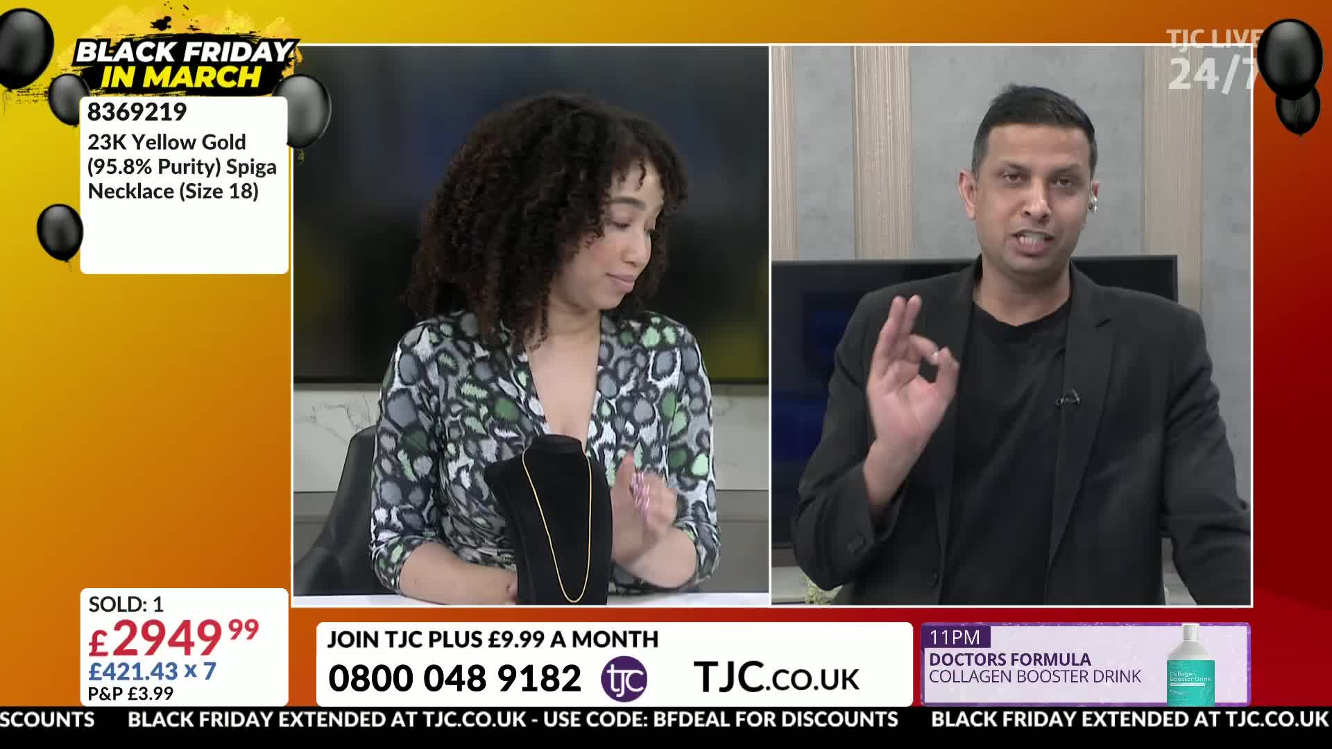 A woman with curly hair presents a delicate gold necklace on a black stand. Beside her, a man in a black blazer gestures with his right hand, his fingers forming a perfect circle.