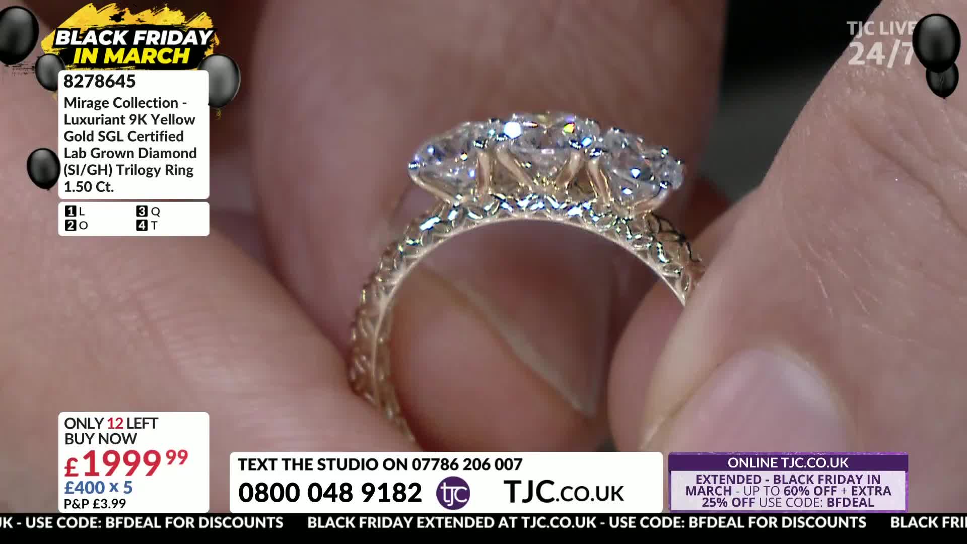 Fingers cradle a 9-carat yellow gold ring, its band intricately patterned. Three brilliant-cut diamonds, each catching the light, are set across the top.