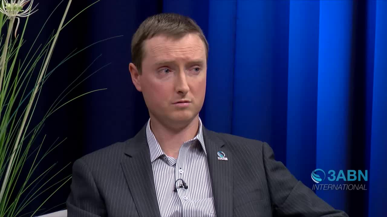 A man in a suit sits facing the camera, a small microphone clipped to his shirt. The 3ABN International logo is visible in the corner of the screen.
