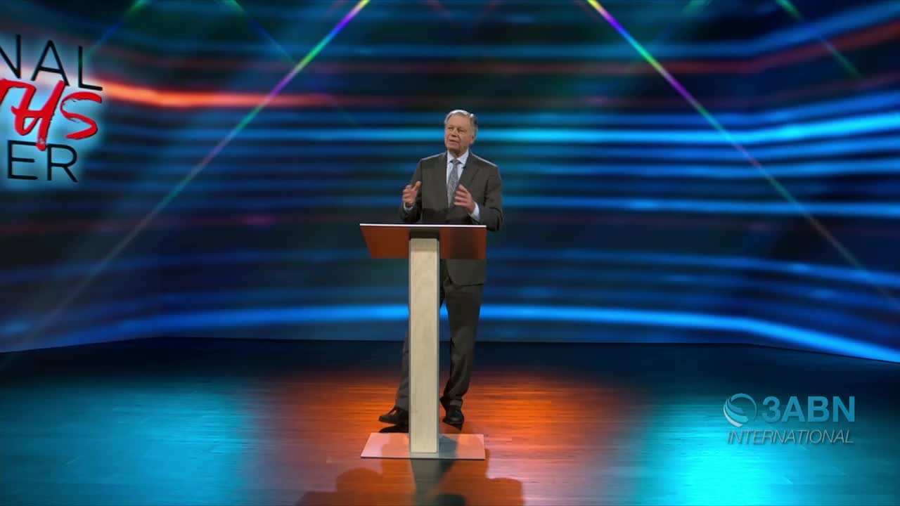 A man in a suit stands behind a podium, gesturing with his hands as he speaks. The backdrop is a stylized blue and orange design, and the logo for 3ABN International is visible in the corner.
