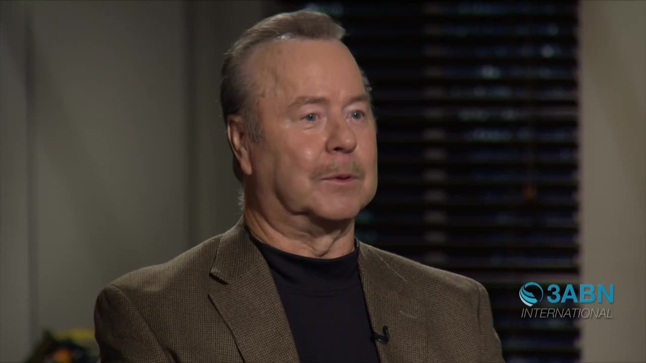 A man with a mustache is speaking, his lips moving as he forms words. Behind him, a window with blinds is visible, and the 3ABN International logo is in the corner.
