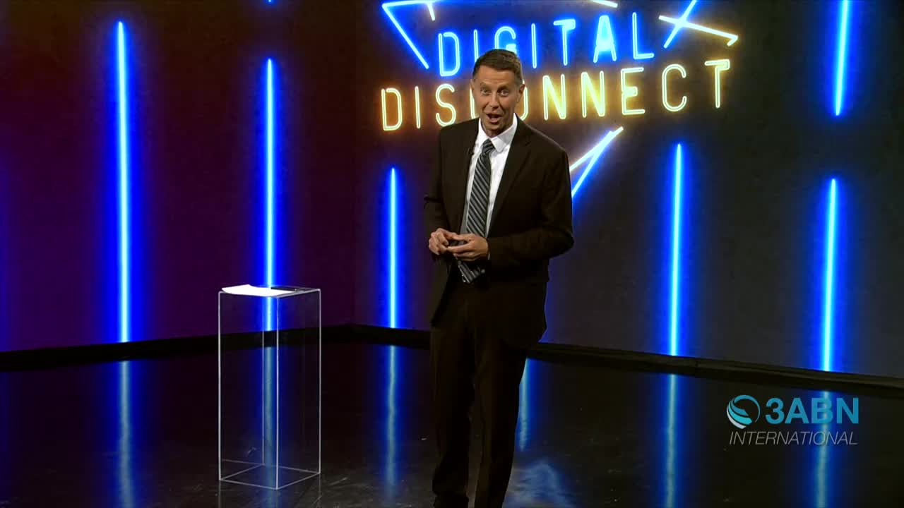 A man in a suit stands center stage, gesturing with his hands. Behind him, the 3ABN International logo is visible, along with the words "DIGITAL DISCONNECT" in neon.
