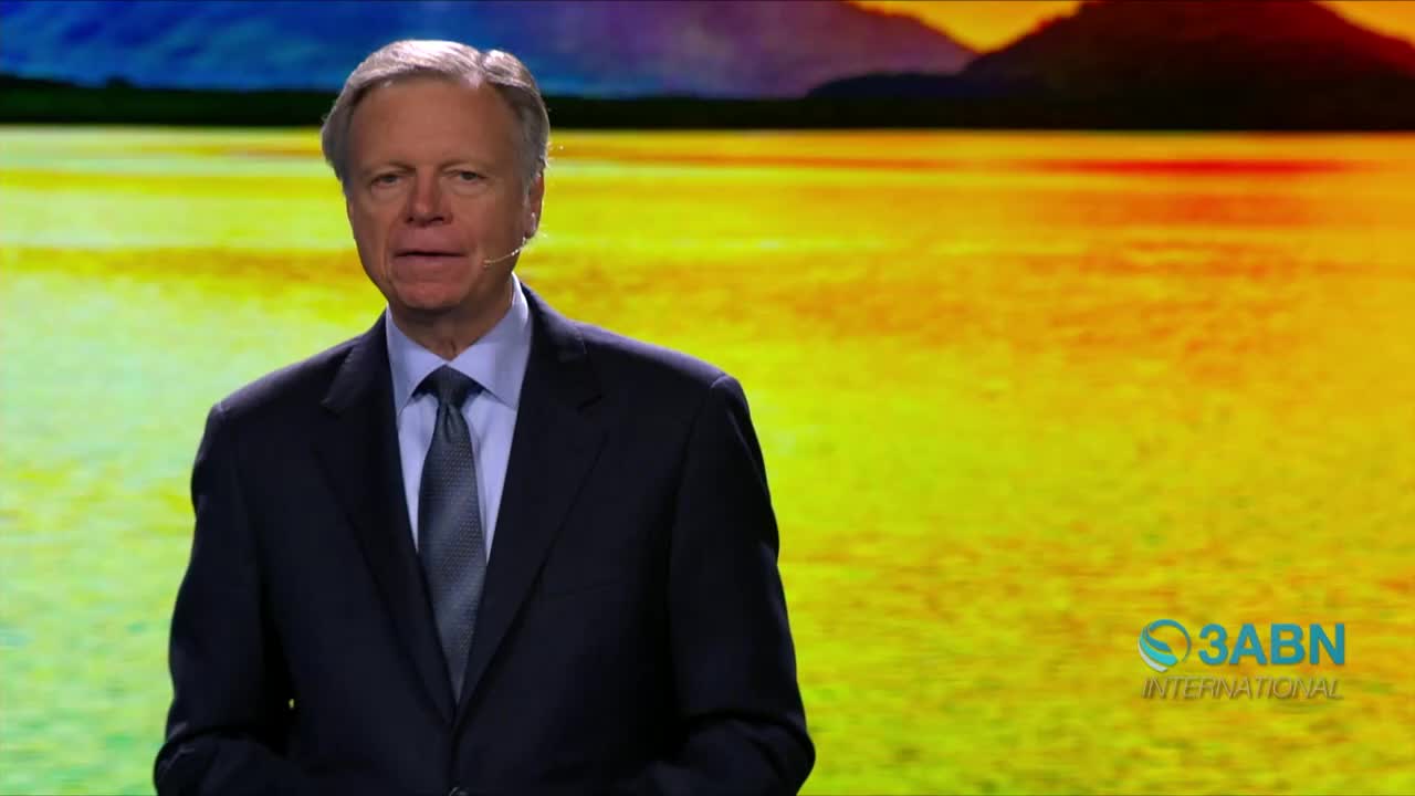 A man in a dark suit speaks, a small microphone clipped to his lapel. Behind him, a vibrant, abstract landscape fills the screen, the 3ABN International logo visible in the corner.
