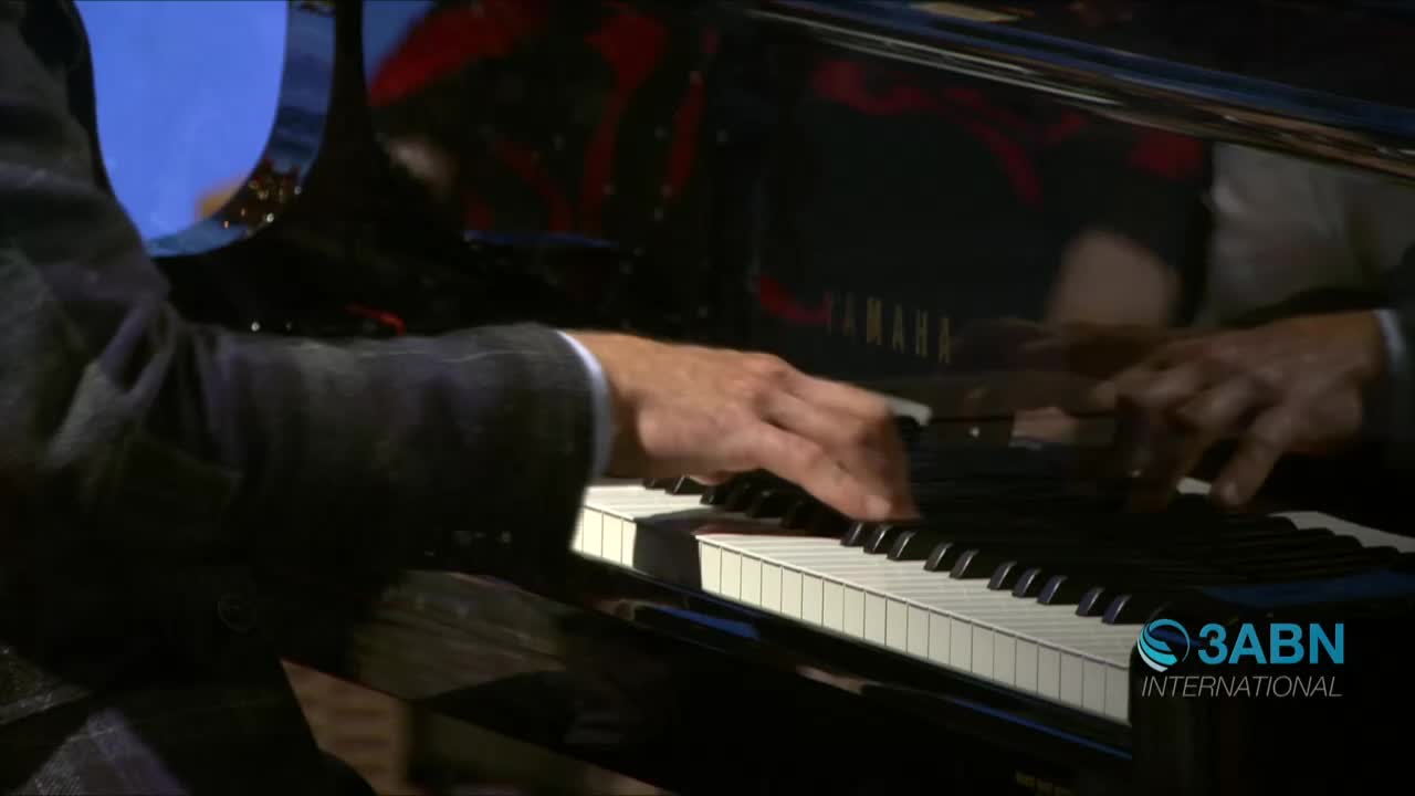 A man in a suit plays a Yamaha piano, his fingers dancing across the keys. The 3ABN International logo is visible in the corner.
