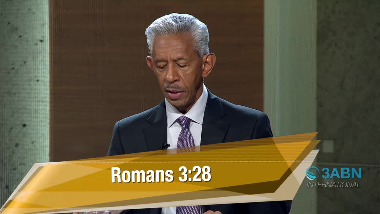 A man in a suit and tie stands before a textured wall, his gaze directed downward. A graphic overlay displays "Romans 3:28" and the 3ABN International logo.