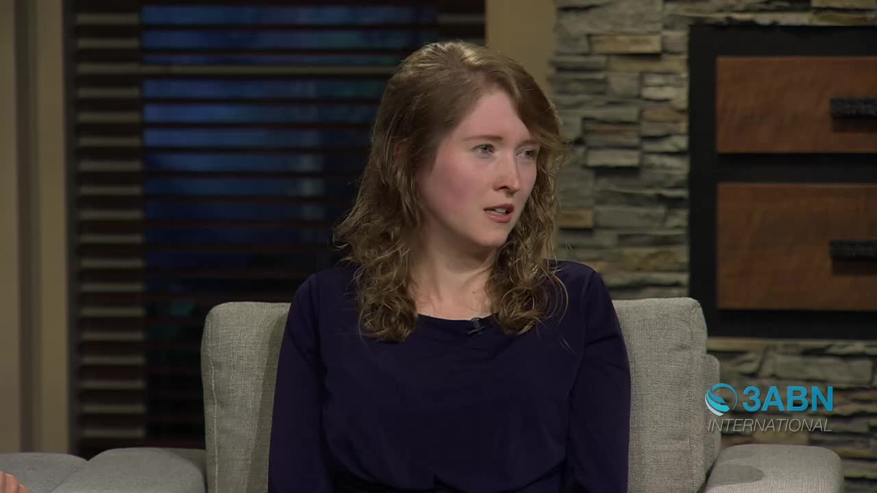 A young woman with wavy blonde hair is speaking, her mouth slightly open. She wears a dark blue long-sleeved shirt and sits in a plush armchair. The 3ABN International logo appears in the lower right corner.