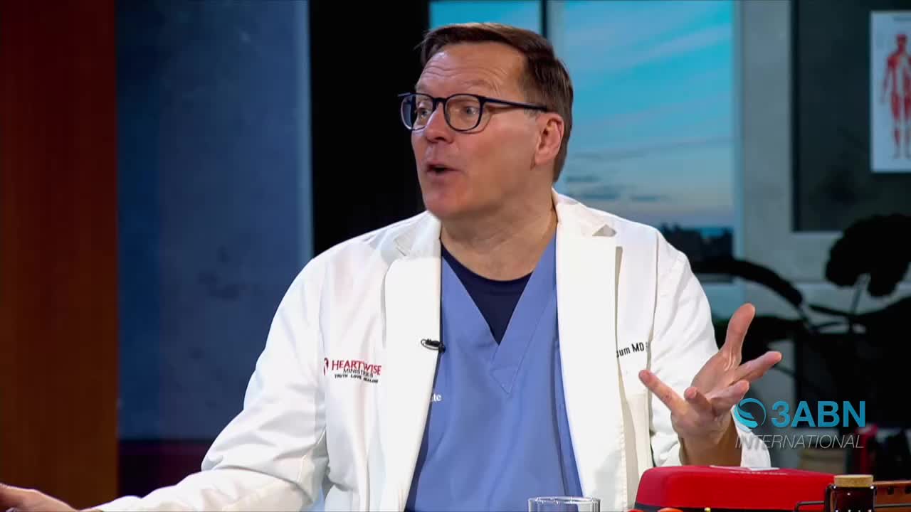 A man in a white lab coat and blue scrubs gestures with his hands as he speaks. A logo for 3ABN International is visible on the right side of the screen.