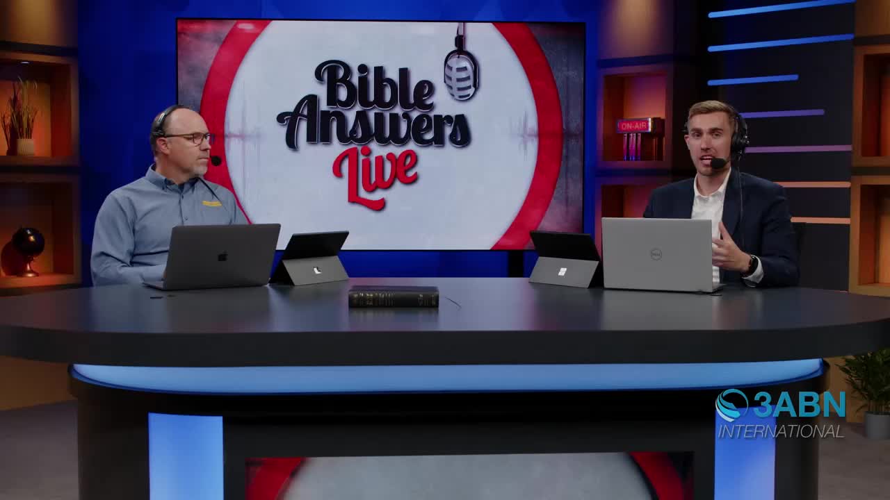 Two men sit at a desk, microphones on, ready to answer questions live. A large screen behind them displays the "Bible Answers Live" logo, a production of 3ABN International.