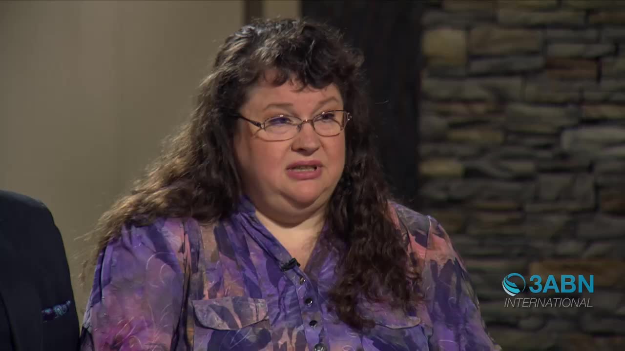 A woman with curly brown hair and glasses speaks, her purple patterned shirt buttoned up. The 3ABN International logo appears in the lower right corner.