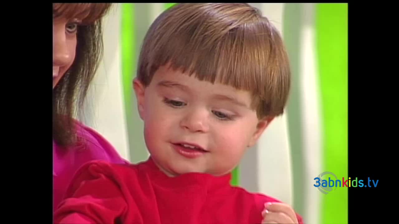 A young child in a red shirt is looking down, mouth slightly open. A woman's arm and face are visible nearby, and the 3abnkids.tv logo is in the corner.

