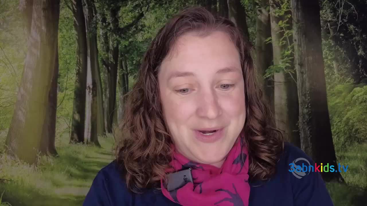 The woman is speaking, her expression open and friendly. Behind her, a backdrop of trees provides a subtle, natural setting, as if she's outdoors.
