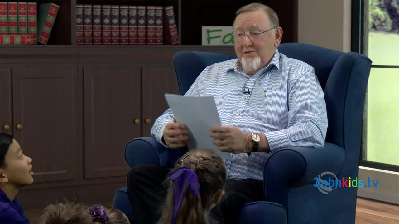 An older man in a blue chair holds a paper, reading aloud to a group of children. The 3ABN Kids logo is visible on the screen.
