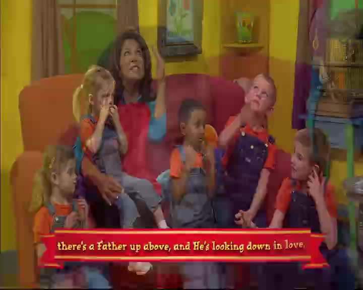 A woman in a red apron sings with a group of children on a couch. The kids wear orange shirts and blue overalls, their faces turned upwards.