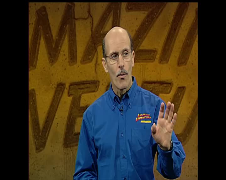 A man in a blue shirt with the 3ABN Kids logo stands in front of a textured yellow wall. He holds up his right hand, palm facing outward.
