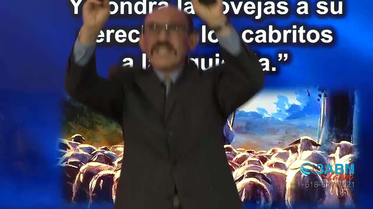 A man in a dark suit gestures wildly, his arms raised as he speaks. Behind him, a graphic of sheep and a blue background are visible, along with the 3ABN Latino logo.
