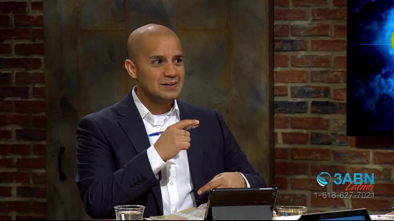 The man in the suit gestures with his right hand, pointing to something off-screen. A logo for 3ABN Latino is visible in the corner.
