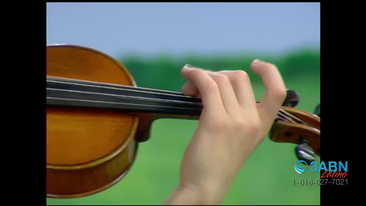 A hand presses down on the strings of a violin, fingers curved over the fingerboard. The instrument's warm wood tones contrast against the green and blue background, as the 3ABN Latino logo appears in the corner.
