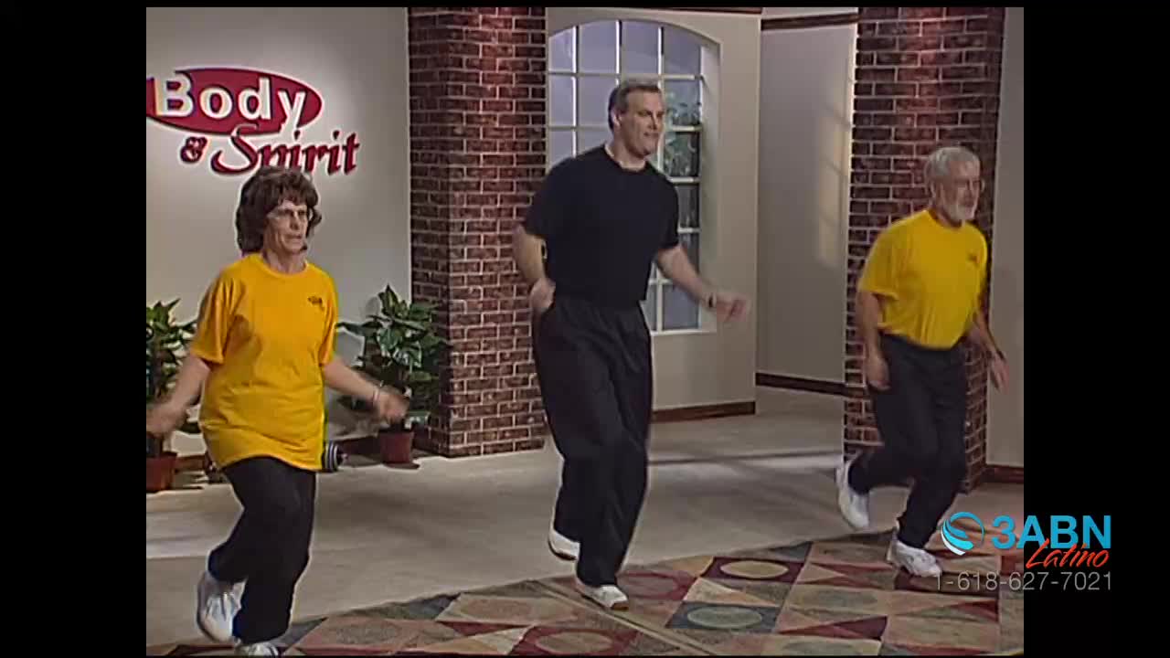 Three people are jogging in place, their arms swinging as they lift their knees. The woman and the older man wear yellow shirts, while the other man wears black.
