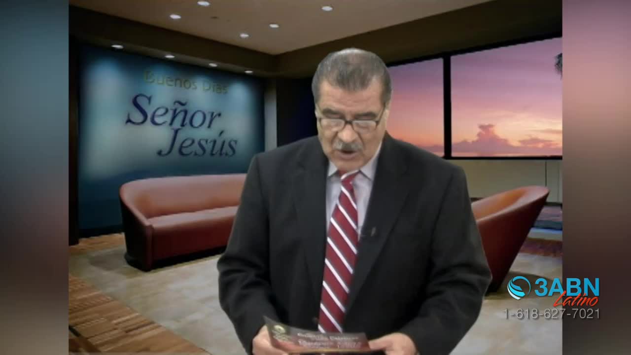 A man in a suit, his face framed by glasses, reads from a pamphlet in a studio setting. Behind him, a backdrop displays "Buenos Días Señor Jesús," while the 3ABN Latino logo is visible in the corner.
