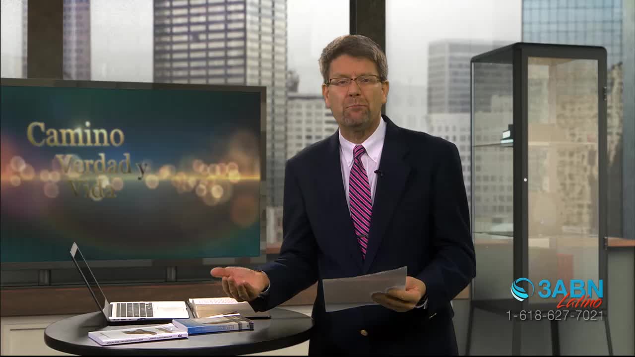 A man in a suit gestures with a paper in his hand, speaking in front of a screen displaying "Camino Verdad y Vida." The 3ABN Latino logo is visible in the corner, suggesting a broadcast from the United States.
