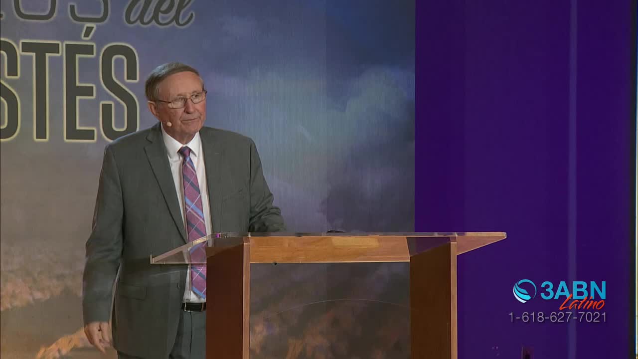 A man in a gray suit and glasses stands behind a wooden podium, speaking. The 3ABN Latino logo is visible on the right side of the screen.
