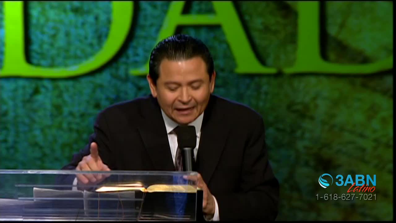 A man in a suit speaks into a microphone, his hand gesturing towards an open Bible on a podium. The 3ABN Latino logo appears in the lower right corner.