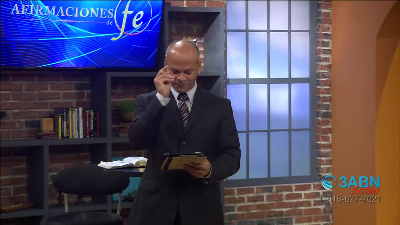 A man in a suit adjusts his glasses while holding a tablet. A screen behind him displays "AFIRMACIONES de fe," and a 3ABN Latino logo is visible in the corner.