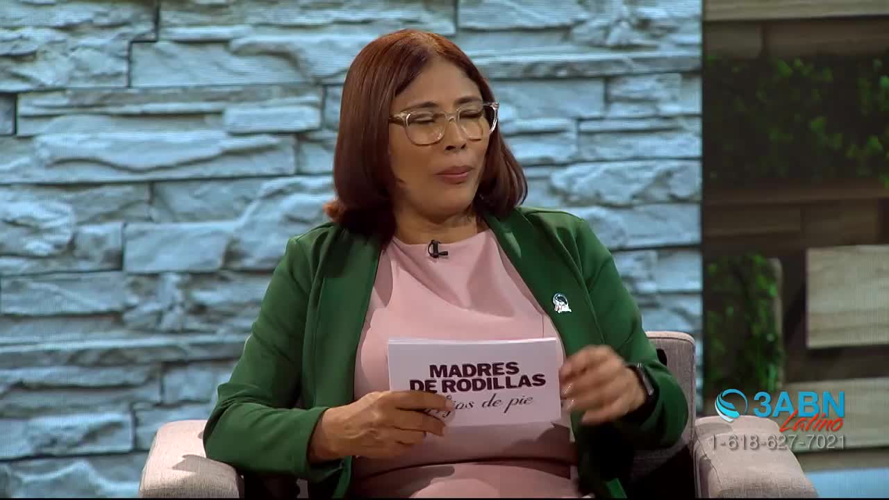 A woman in a green jacket and pink shirt holds a card with Spanish text.  A 3ABN Latino logo appears in the lower right corner.