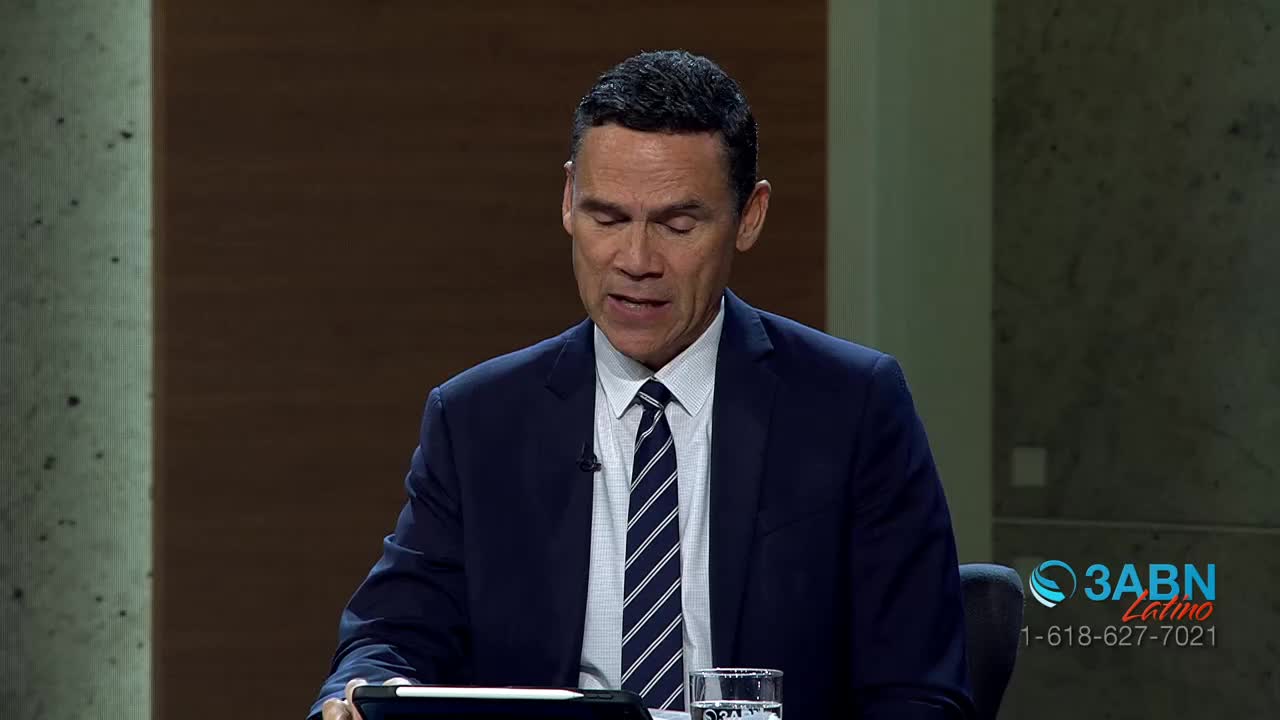 A man in a dark suit and striped tie speaks into a microphone. A logo for 3ABN Latino appears in the lower right corner.