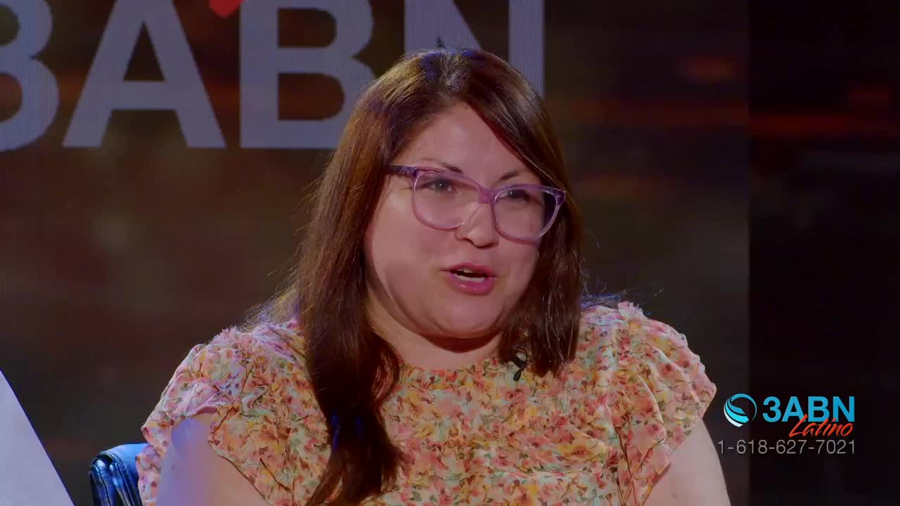 A woman with auburn hair and purple glasses speaks animatedly, her floral blouse a soft pattern against the dark background. The 3ABN Latino logo appears in the corner, a familiar sight for viewers in the United States.