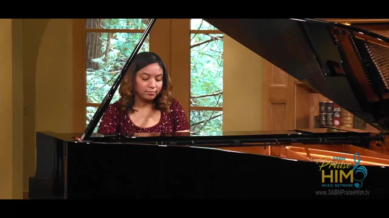 A woman in a sparkling red top plays a grand piano, her fingers dancing across the keys. Through the window, I can see a lush green landscape, and the 3ABN Praise Him Music Network logo is visible in the corner.
