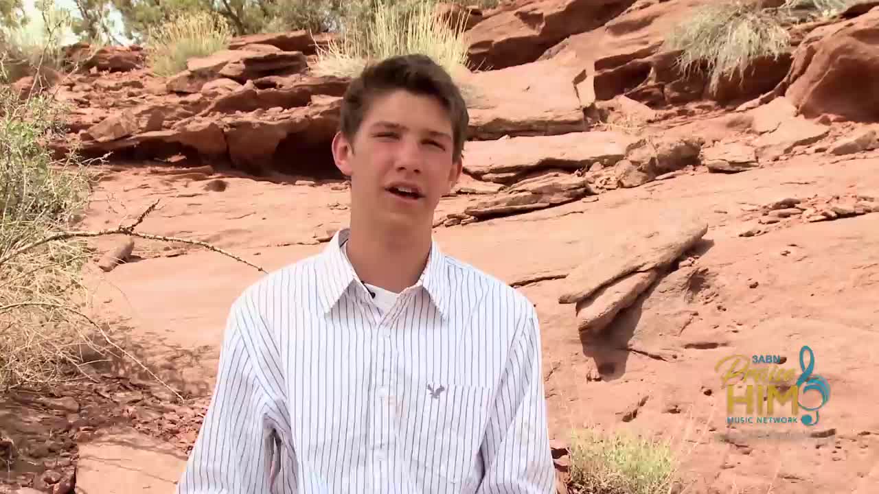 A young man, wearing a striped shirt, speaks in front of a red rock formation. The 3ABN Praise Him Music Network logo is visible in the bottom right corner.
