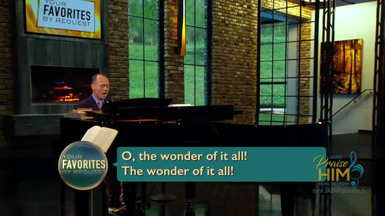 A man in a suit sings and plays a grand piano. The words "O, the wonder of it all!" appear on a screen in front of him.
