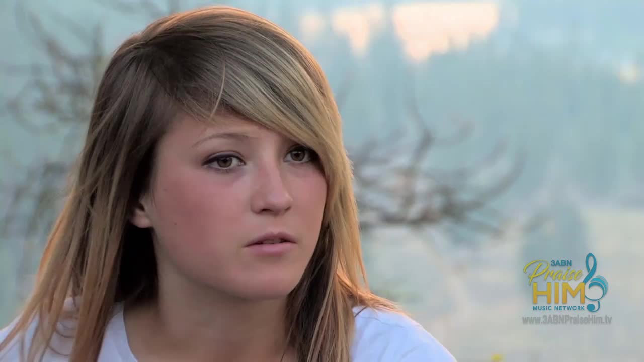 A young woman with blonde hair and a white shirt gazes off-camera, her expression thoughtful. The logo for 3ABN Praise Him Music Network is visible in the corner.
